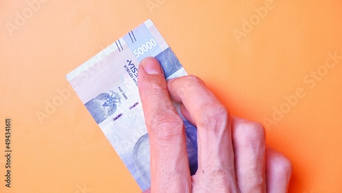 Indonesian Rupiah the official currency of Indonesia. Man's hand is making a payment. Male hand showing Indonesian Rupiah note. Business Investment Economy and Finance concept Uang 50000 50.000 Rupiah