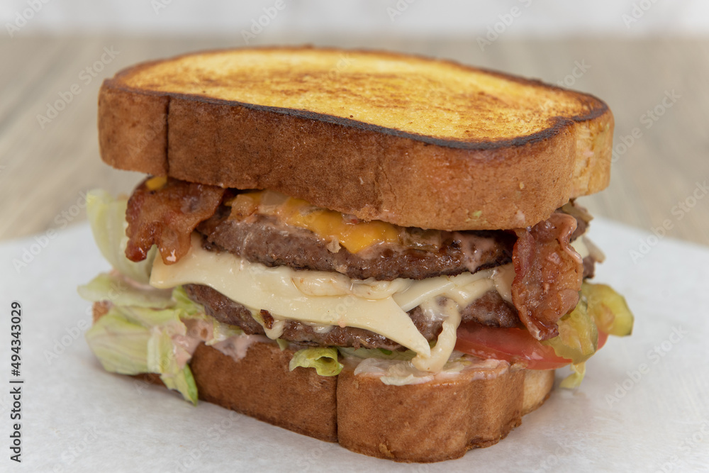 Enormous garlic bread double deck cheeseburger loaded wih bacon and lettuce for a huge appetite Enormous garlic bread double deck cheeseburger loaded wih bacon and lettuce for a huge appetite