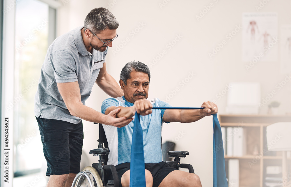 Obraz premium This exercise is also great for maintaining good balance. Shot of a senior man in a wheelchair exercising with a resistance band along side his physiotherapist.