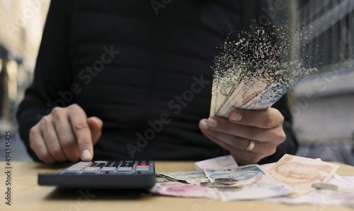 Closeup of a hand holding disappearing banknotes - financial crisis concept photo
