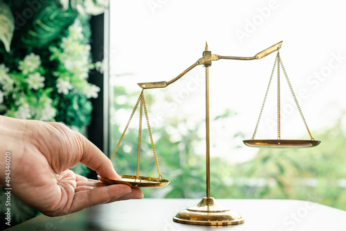 Tip the scales of justice concept as a the hand of a person illegally influencing the legal system for an unfair advantage.