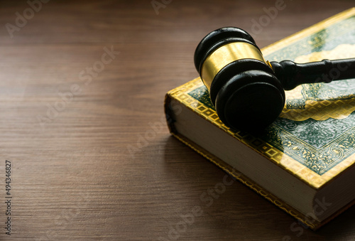 Sharia or Islamic law concept with gavel and Quran on wooden background. photo