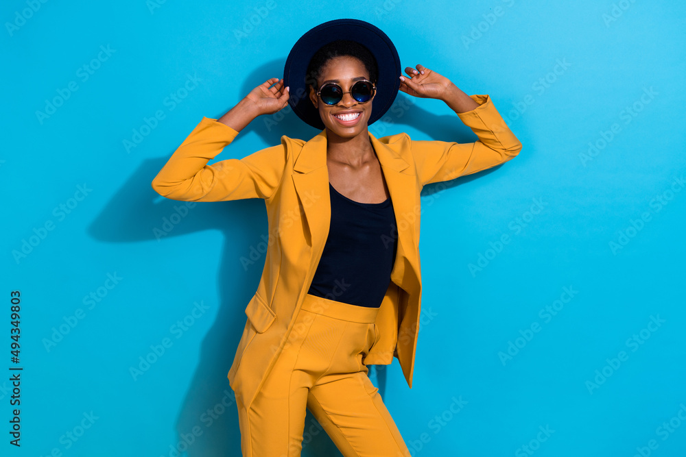 Portrait of funny cheerful lady hands touch hat toothy smile enjoy vacation isolated on blue color background