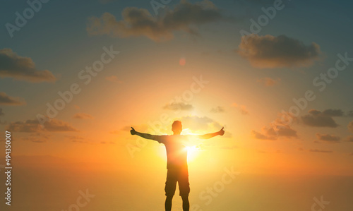 Feeling positive. Young man with thumbs up looking to the sunrise. Feelings of hope and gratitude 