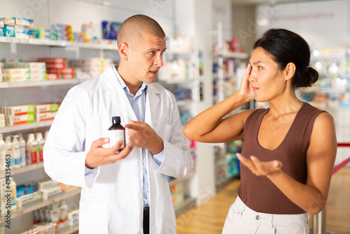 Woman buyer asks for help of pharmacist to choose medicine for headache