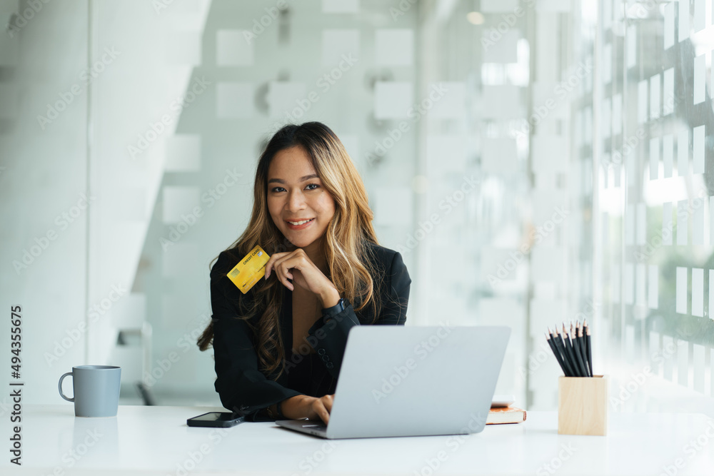 Young woman holding credit card and using laptop making payment online. Businesswoman or entrepreneur working at home. Online shopping, e-commerce, banking, internet store, spending money concept Young woman holding credit card and using laptop making payment online. Businesswoman or entrepreneur working at home. Online shopping, e-commerce, banking, internet store, spending money concept