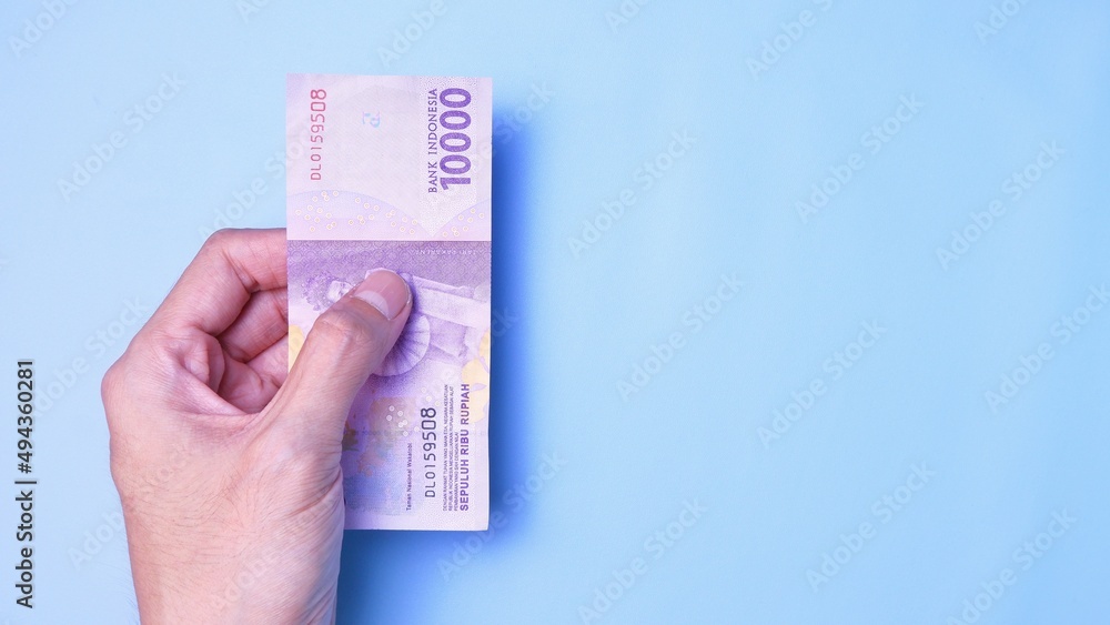 Indonesian Rupiah the official currency of Indonesia. Man's hand is making a payment. Business Loan Income Money Investment Economy and Finance Concept Uang 10000 10.000 Rupiah. Prosperity Concept. Indonesian Rupiah the official currency of Indonesia. Man's hand is making a payment. Business Loan Income Money Investment Economy and Finance Concept Uang 10000 10.000 Rupiah. Prosperity Concept.