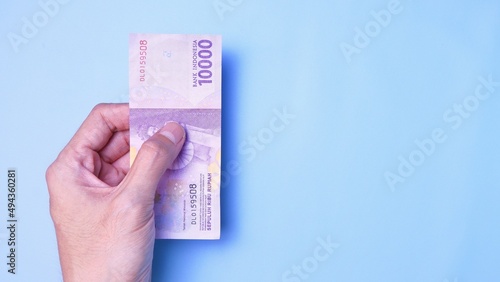 Indonesian Rupiah the official currency of Indonesia. Man's hand is making a payment. Business Loan Income Money Investment Economy and Finance Concept Uang 10000 10.000 Rupiah. Prosperity Concept.