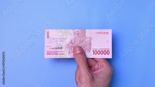 Indonesian Rupiah the official currency of Indonesia. Man's hand is making a payment. Business Loan Income Money Investment Economy and Finance Concept Uang 100000 100.000 Rupiah. Prosperity Concept.