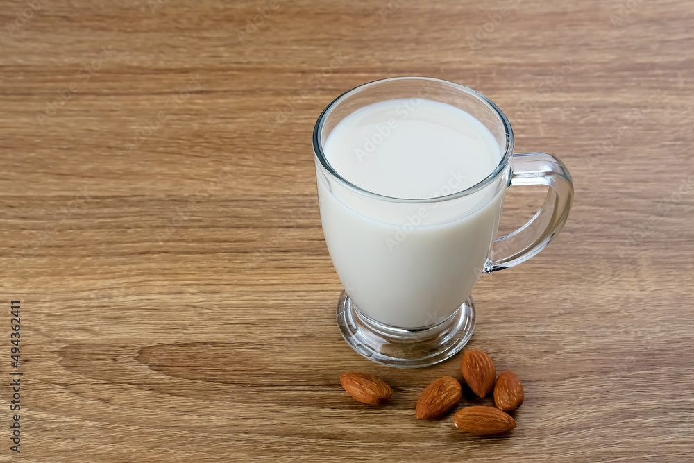 Almond milk in glass with almonds on the table. Space for text
Almond milk in glass with almonds on the table. Space for text