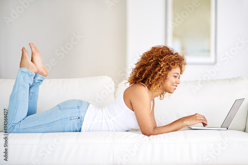 Uncapped wifi all weekend long. Shot of a young woman using a laptop on the sofa at home.