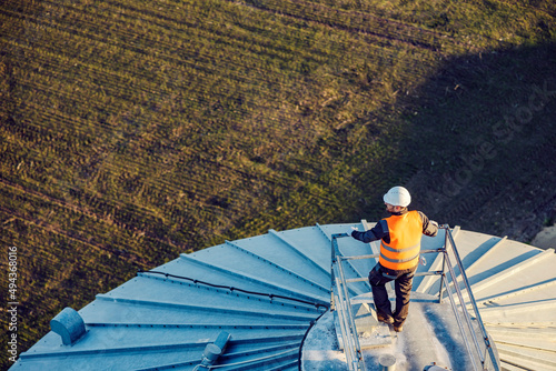 Aerial view of an industry worker standing on top of the silo. photo