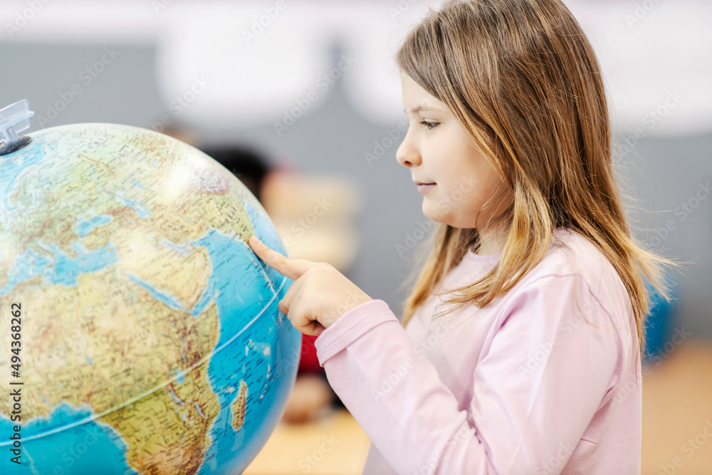 A schoolgirl pointing at the globe at geography class. A schoolgirl pointing at the globe at geography class.