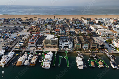 Boats docked in front of Bech homes at harbor with ocean view during early morning in Newport Beach California