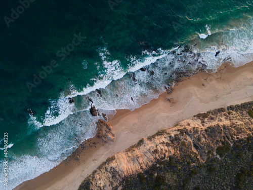 Green / Blue Ocean Waves coming ashore at Crystal Cove California with rock cliffs at sunset