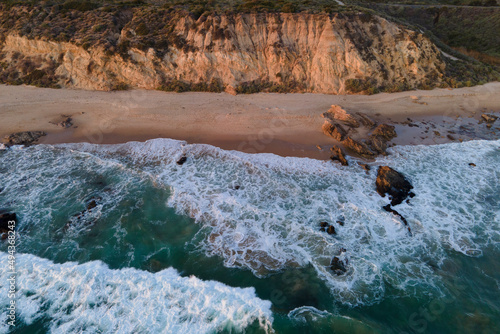Green / Blue Ocean Waves coming rolling at Crystal Cove California with rock cliffs at sunset