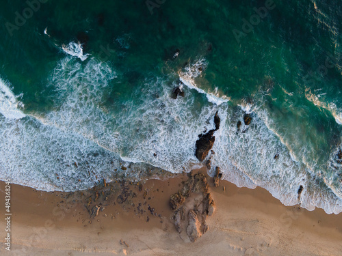 Green / Blue Ocean Waves coming rolling at Crystal Cove California with rock cliffs at sunset