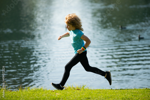 Kids running outdoors. Run and healthy sport for children. Child running on summer field near lake, kids fitness. Kids running on green meadow against sea or lake.