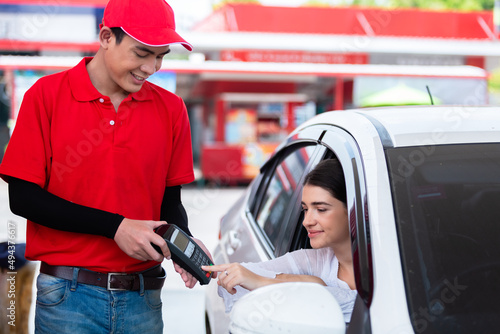 Woman in car paying card reader payment terminal after refuel car ​spending instead of cash with man service employee at gas station. petrol business finance energy concept. photo