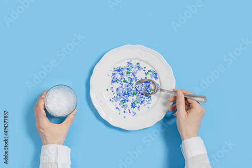 Plate with plastic pieces instead of food and glass of microplastics instead of water. Microplastic problem concept, ocean pollution ecology problem, environmental impact on nature, top view photo