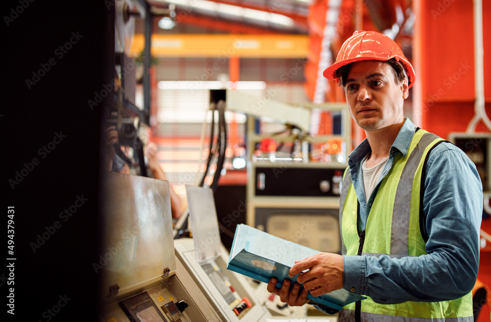 Men industrial engineer wearing a white helmet while standing in a heavy industrial factory behind. The Maintenance looking of working at industrial machinery and check security system setup in fact Men industrial engineer wearing a white helmet while standing in a heavy industrial factory behind. The Maintenance looking of working at industrial machinery and check security system setup in fact