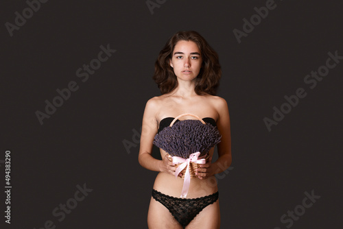 Skin care body. Girl is gainst procedure hair removal. Hair on legs and in bikini area women in black shorts with lavender. Positive body, self-image feminism. Self acceptance is body positive. photo