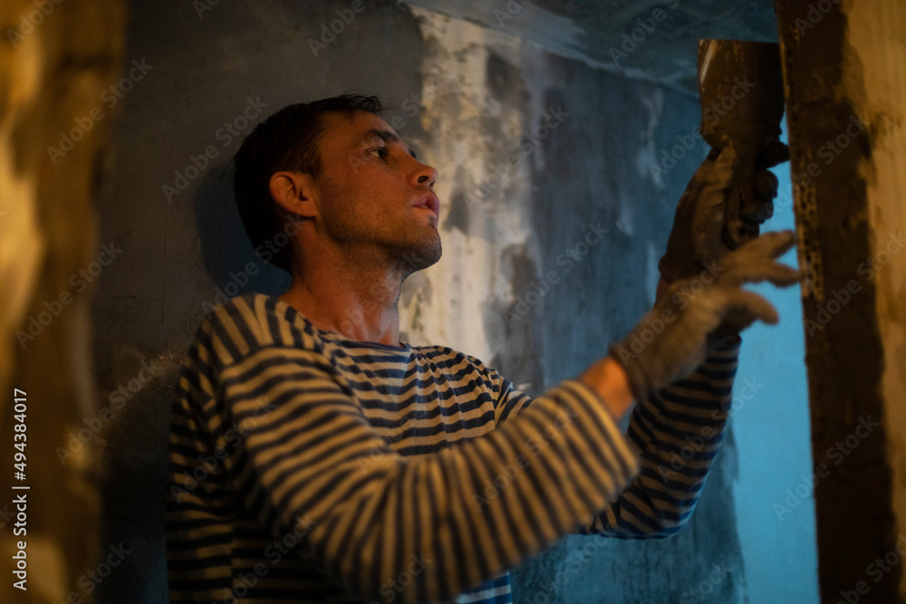 Guy is doing wall repairs. Man makes flat wall. Cement application. Guy is doing wall repairs. Man makes flat wall. Cement application.
