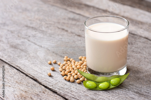 Glass of soy milk with soybean isolated on rustic wooden table background.