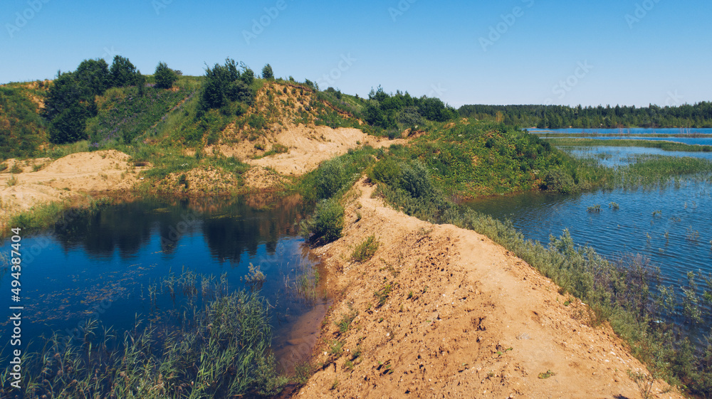 Flooded sand quarry near Sychevo. Lush green summer landscape for outdoors vacation, hiking, camping or tourism. Volokolamsk district of Moscow region. Russia