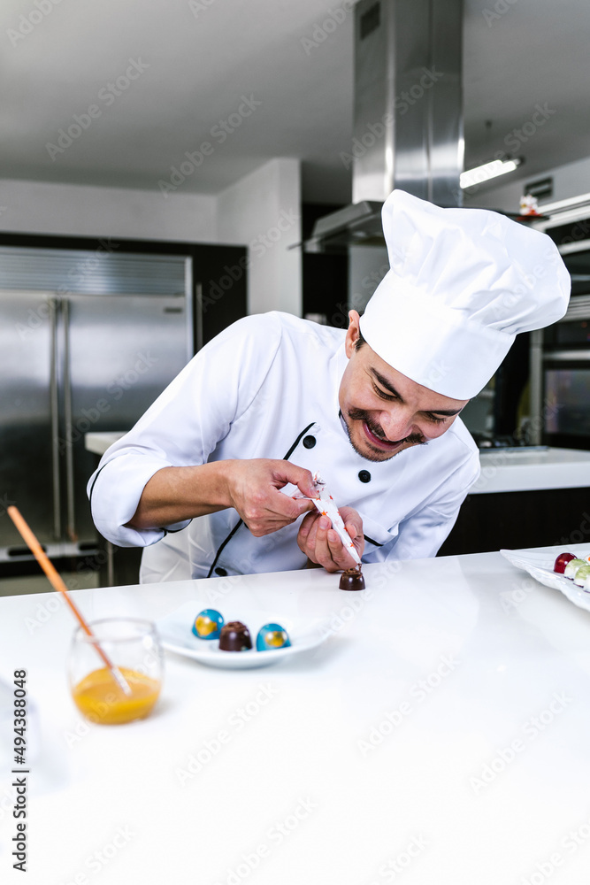 hispanic man pastry chef wearing uniform in process of preparing delicious mexican sweets chocolates at kitchen in Mexico Latin America
