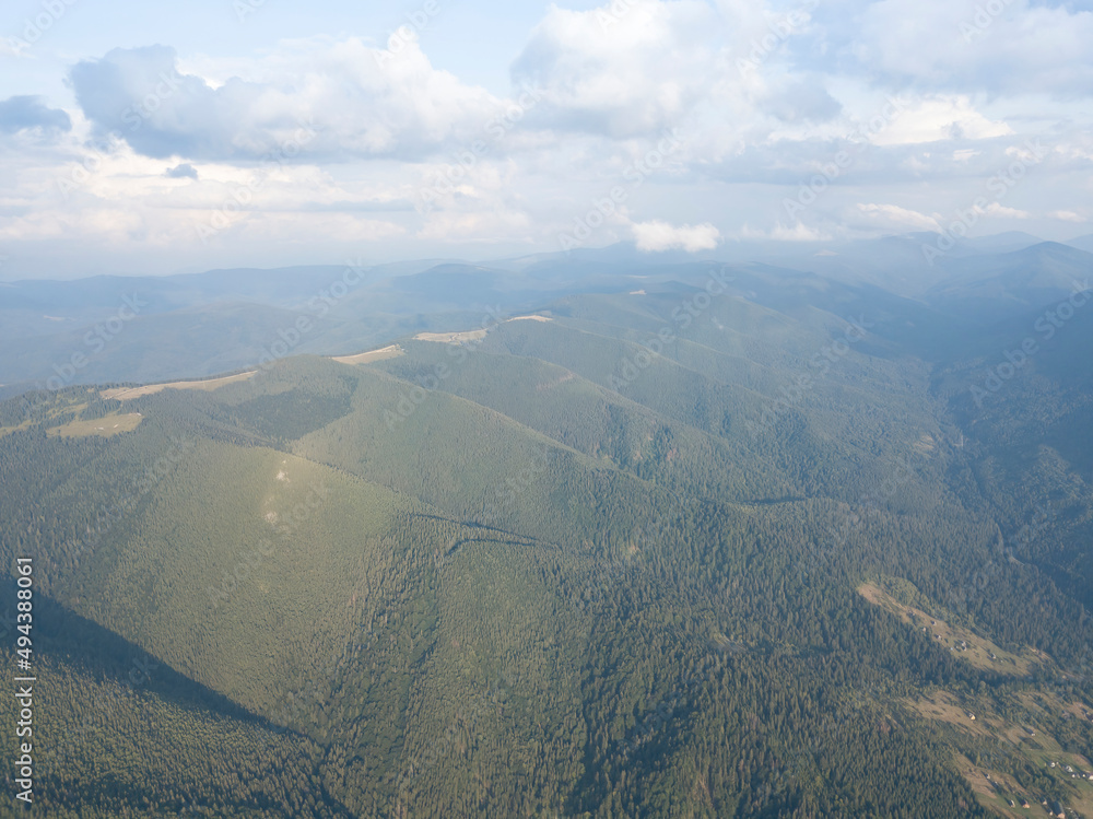 Obraz premium Green slopes of Ukrainian Carpathian mountains in summer. Cloudy day, low clouds. Aerial drone view.