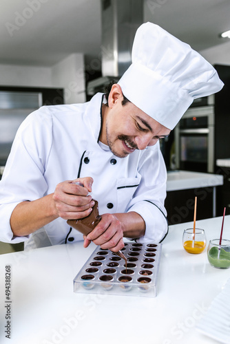 hispanic man pastry chef wearing uniform in process of preparing delicious mexican sweets chocolates at kitchen in Mexico Latin America