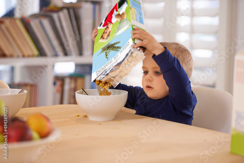 Hes making his own breakfast. Cropped shot of a young boy pouring his breakfast into a bowl at home.