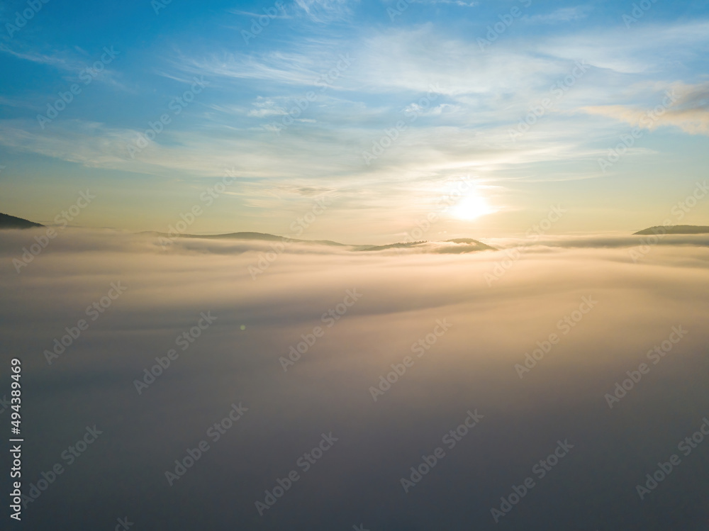 The rays of dawn over the fog in the Ukrainian Carpathians. Aerial drone view.