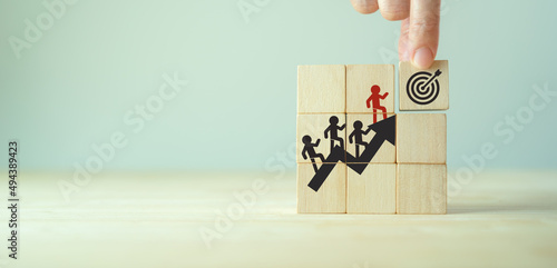 Common goal success concept. Leader, team rises up stairs to goal and achieve successful business. Initiation for planning to reach target. Darts target aim icon on wooden cubes with grey background. photo