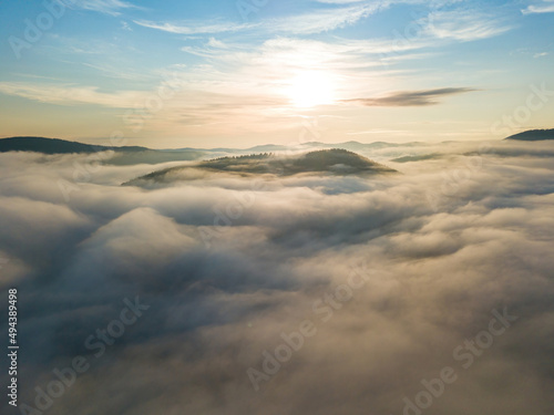 The rays of dawn over the fog in the Ukrainian Carpathians. Aerial drone view.