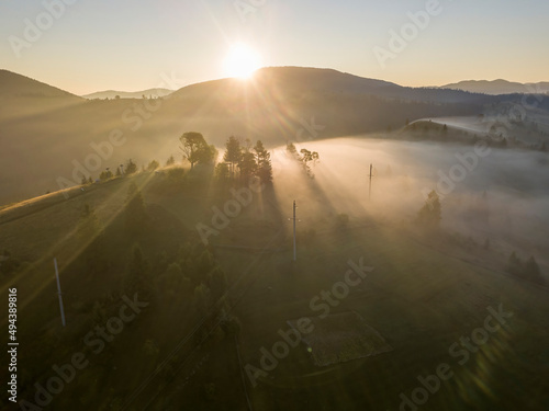 The rays of the morning sun through the fog in the mountains. Aerial drone view. © Sergey