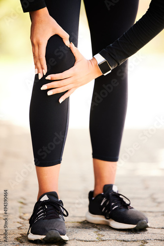 Shes having a little trouble with her knee. Cropped shot of an unrecognizable and athletic woman holding her knee in discomfort while standing outdoors.