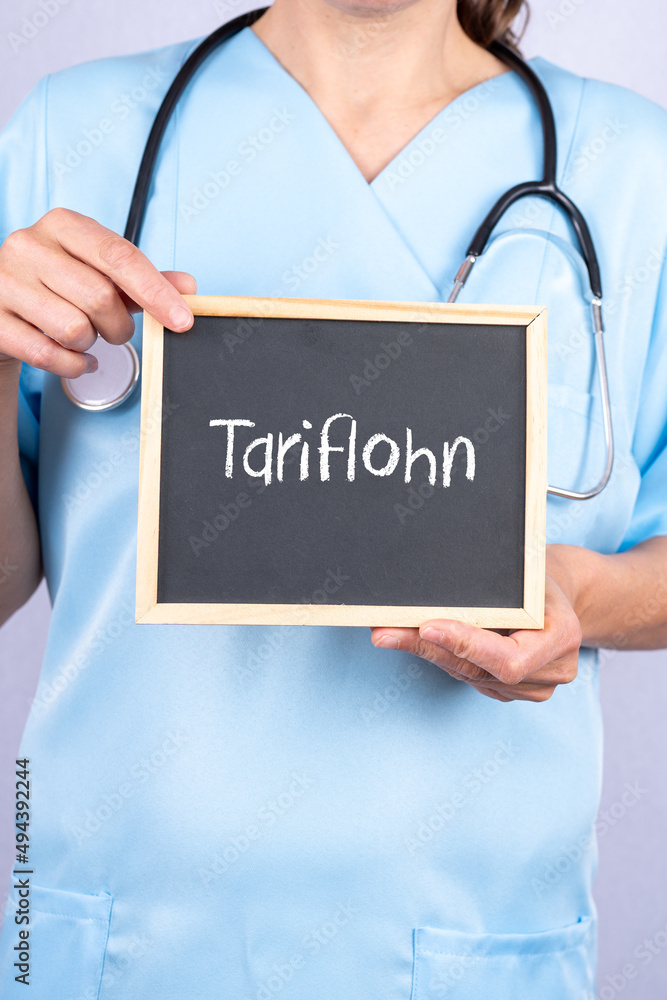 Krankenschwester oder Altenpflegerin zeigt auf eine Tafel auf der Tariflohn steht Krankenschwester oder Altenpflegerin zeigt auf eine Tafel auf der Tariflohn steht