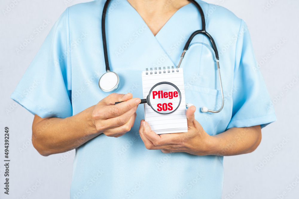 Eine Pflegekraft oder Krankenschwester hat eine Lupe in der Hand die Pflege SOS zeigt Eine Pflegekraft oder Krankenschwester hat eine Lupe in der Hand die Pflege SOS zeigt