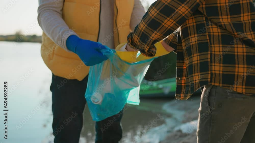 Happy caucasian father and son cleaning river from plastic, finishing and doing high-five enjoying teamwork activity outside. Ecology volunteers. Family. Happy caucasian father and son cleaning river from plastic, finishing and doing high-five enjoying teamwork activity outside. Ecology volunteers. Family.