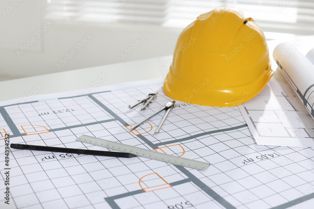 Construction drawings, safety hat and stationery on table in office Construction drawings, safety hat and stationery on table in office