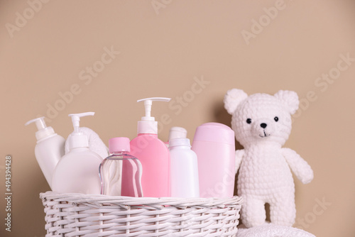 Wicker basket with baby cosmetic products and knitted toy bear on beige background © New Africa