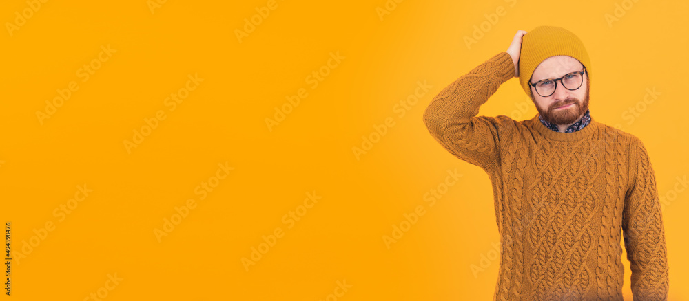 Young frustrated Caucasian man looking at the camera and touching his head with his hand portrait copy space orange background isolated . High quality photo Young frustrated Caucasian man looking at the camera and touching his head with his hand portrait copy space orange background isolated . High quality photo