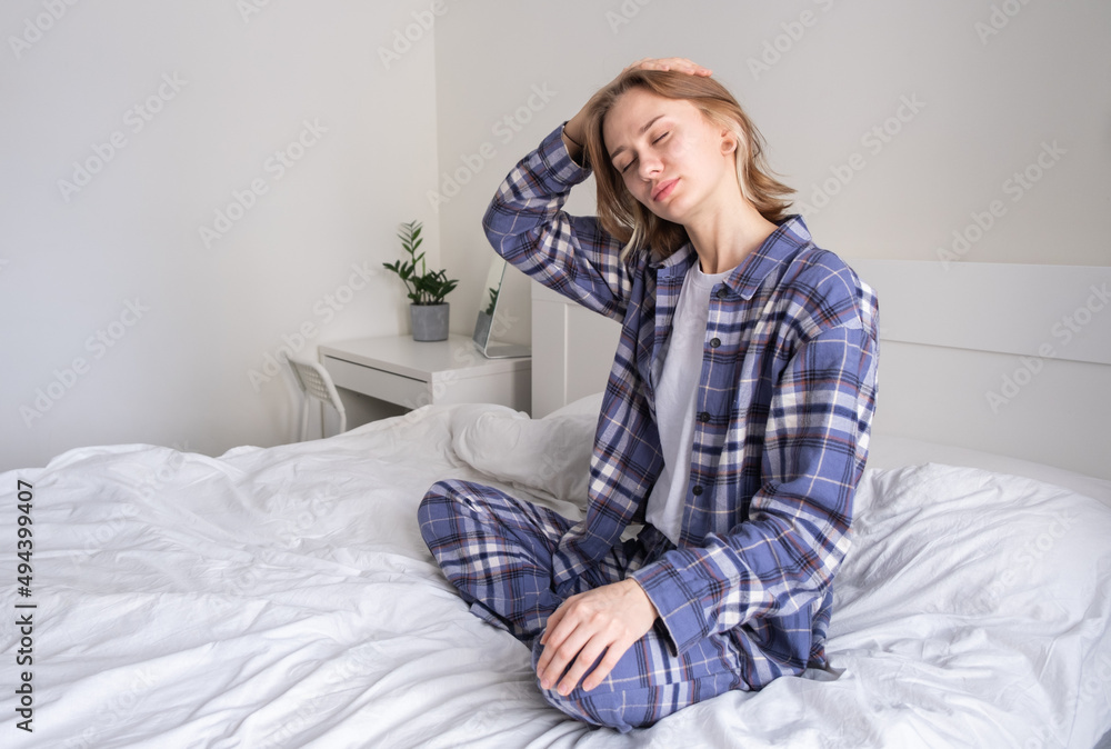 A beautiful girl does neck exercises while sitting on the bed. A young woman makes sure her spine is healthy in the morning. A beautiful girl does neck exercises while sitting on the bed. A young woman makes sure her spine is healthy in the morning.
