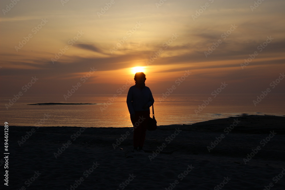 silhouette of a person standing on the beach at sunset