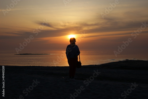 silhouette of a person standing on the beach at sunset