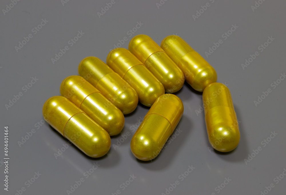 Golden pills on a gray background as a symbol of expensive drugs. Expensive medicines and health care in case of illness. Medical business on medicines. Golden pills on a gray background as a symbol of expensive drugs. Expensive medicines and health care in case of illness. Medical business on medicines.