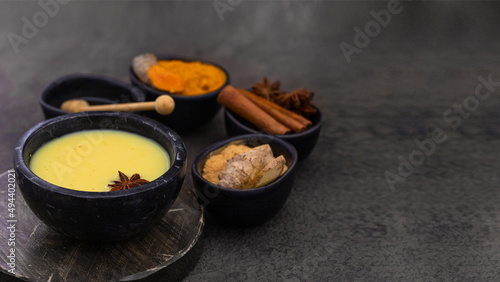 Ayurvedic drink Golden milk with ingredients ginger, turmeric honey and spices on dark background. Alternative remedies for health