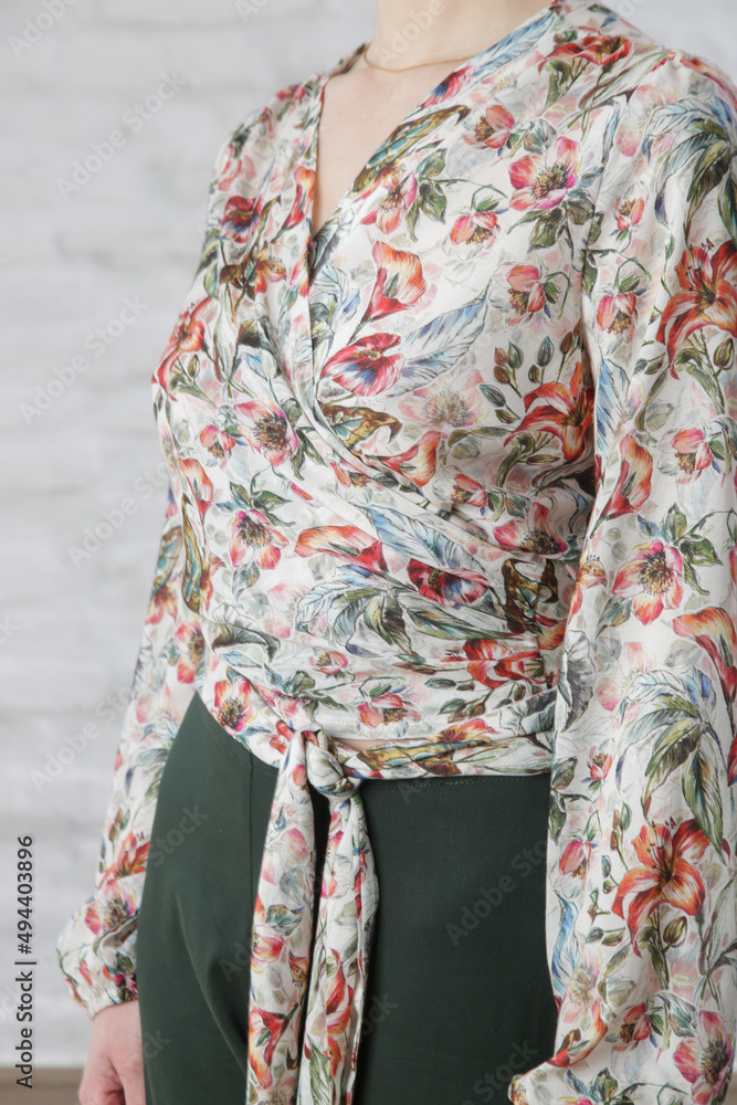 Woman in floral wrap blouse, studio shot.	